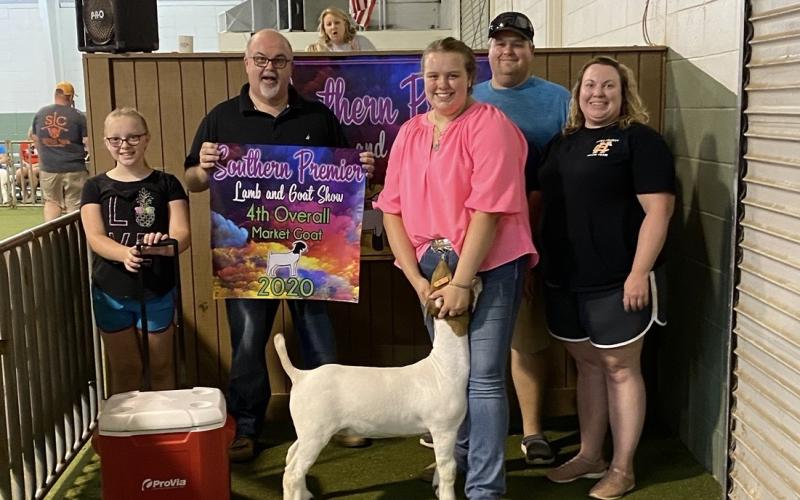 Avery Adams took fourth place overall at the Southern Premier Lamb and Goat Show in Tifton. She is pictured with a show representative and her family. 