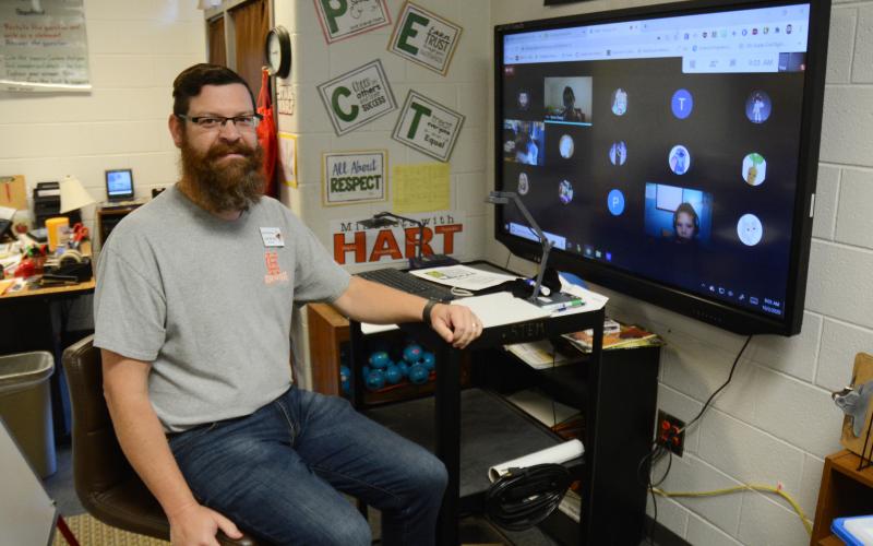 Sunshot by MIchael Hall - Josh McCurley poses for a photo at his virtual learning station where he is teaching third-grade virtual learners and will use a Bright Ideas Grant from Hart EMC to teach them circuitry. 