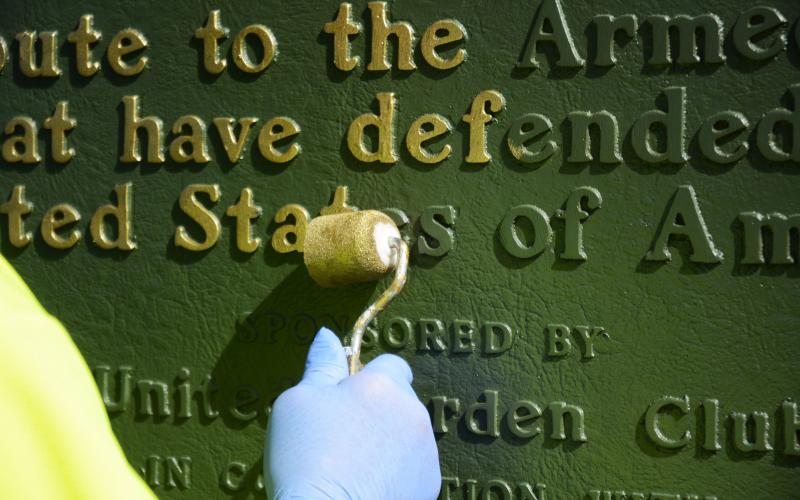 Tom Stelling does the detail work of painting the letters of the Blue Star Memorial gold. 