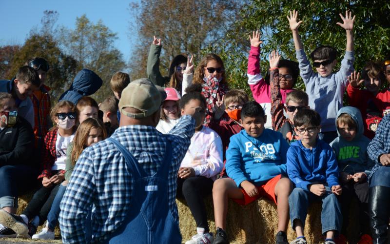 Students eagerly raise their hands to answer questions asked by assistant principal Steve Burton following a hay ride as part of Ag-Day.