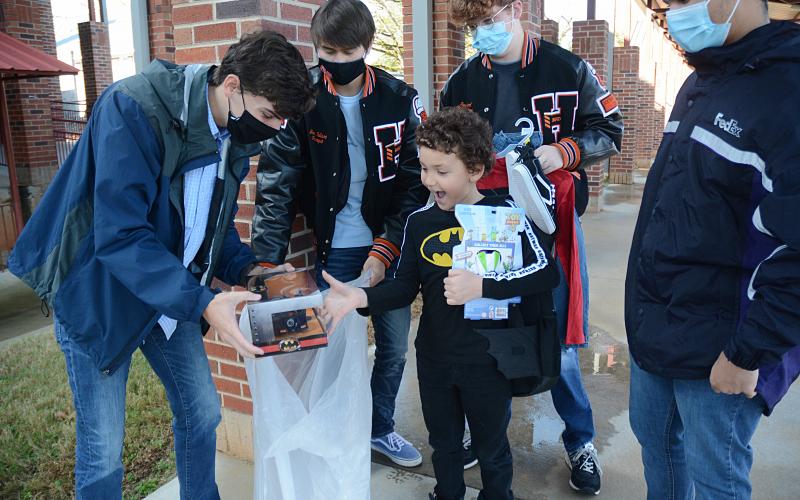 Hart County High School seniors Adam Walters, from left, Ben Tellano, Sean Leard and Tahj Courage give gifts they bought at Walmart to Damien Jones, a second-grader at Hartwell Elementary. 