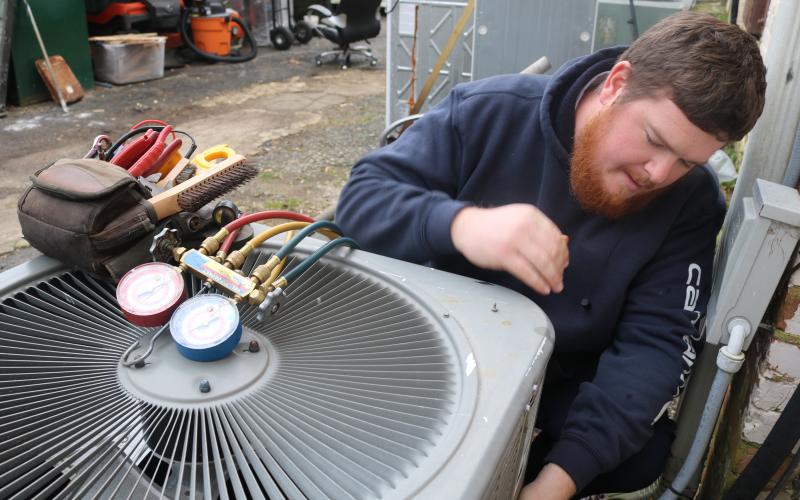 Sunshot by Grayson Williams - McGee Heating and Air technician Kyle Risner, a Hartwell native,  makes repairs to an air conditioning unit recently in Hartwell.