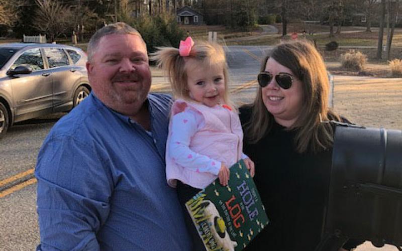 Charlie and Kim Pierce pose for a picture with their daughter, Camille, and a book provided by the Imagination Library.  Photo submitted