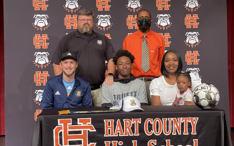 Justin Heard, seated center, signed to play soccer at Truett McConnell University alongside, seated left, Truett McConnell coach Stephen Lee, seated right, mother Wanda Heard, standing left, coach Ben Hudson, and, standing right, father Ronald Lee Heard.