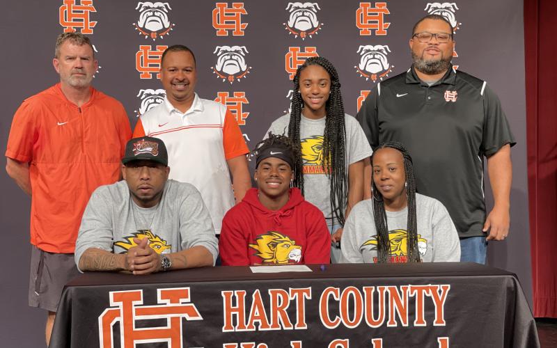 Quinn Moore, seated center, signed to Emmanuel College’s track team alongside, seated left, stepfather Allen Perry Jr., and seated right, mother Tosha Perry. Also pictured from left to right, back row, coach Taz Dixon, coach Floyd Ramsey, Moore’s sister Takyra Daniels and coach Kendell Rucker.