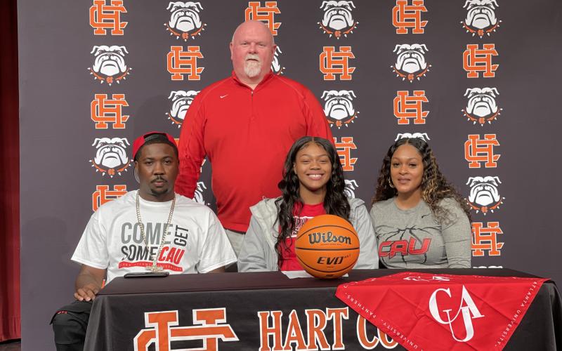 Taniya “Nesha” Alexander, seated center, signed to play basketball with Clark-Atlanta University alongside her father Charleston Alexander, seated left, her mother Tammy Scott, seated right, and coach Mike Edwards, back.