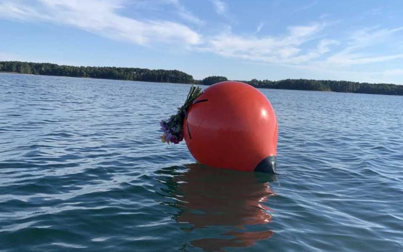 An unknown visitor attached a memorial bouquet Tuesday to the buoy that marks the spot of which a single-engine plane entered Lake Hartwell on Saturday, Sept. 10. The plane was still underwater by press time Wednesday. One passenger, the pilot, was assumed dead upon impact. Excavation crews were scheduled to lift the plane from the lake depths Thursday.