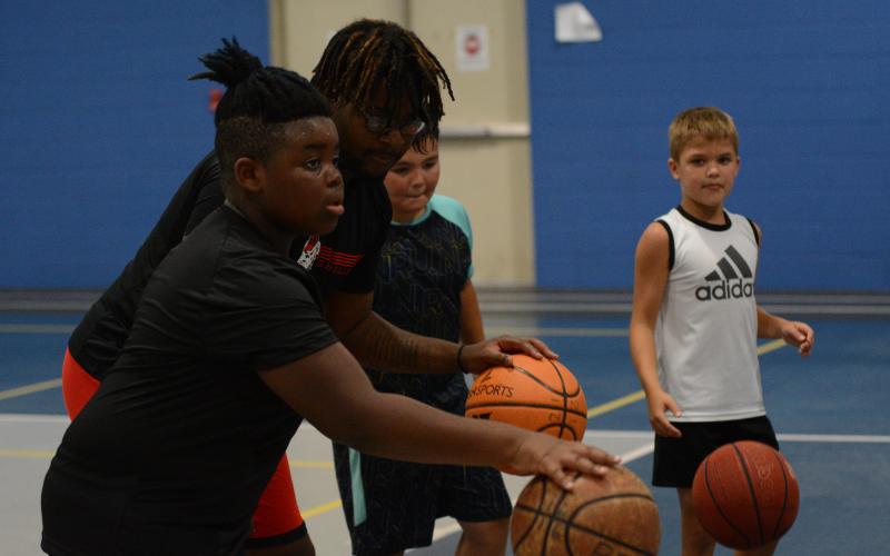 Pictured from left to right is Jeremy Dunkins, Nyje Willis, Jackson Dallas, and Logan Hubbard as they walk through a dribbling drill during the YMCA basketball camp.