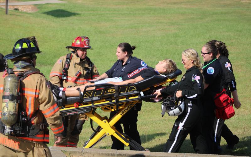 Firefighters, EMS, and a Med-Trans Life Flight crew transport a student who acted as a “victim” during the drill. 