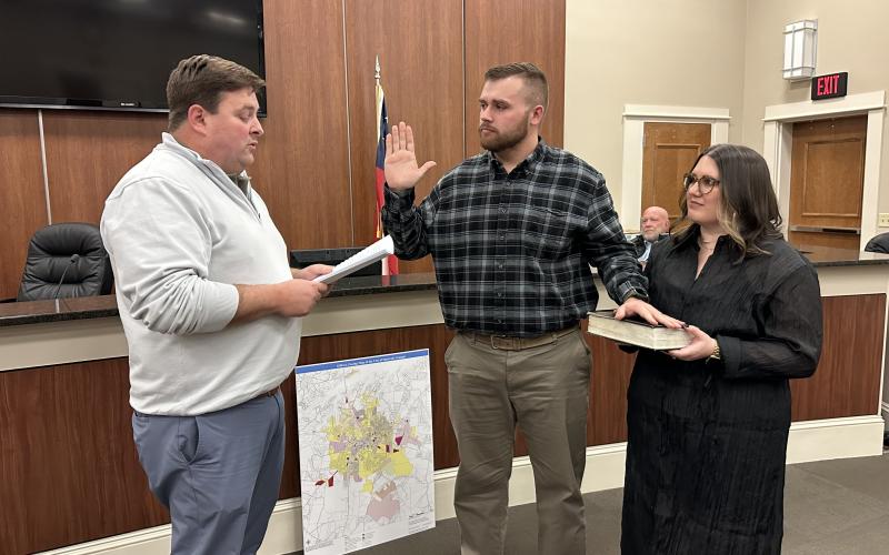 With his wife Emilee (right) holding the Bible, Zach Adams (center) was sworn in to his new position as a Hartwell City Council member by City Manager Jon Herschell (left).