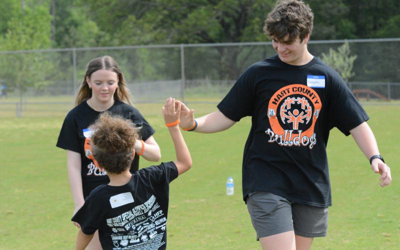 HCHS sophomores Kenyon Harris (right) and Maeleigh Agnew (behind on the left) celebrate with an Special Olympic athlete after completing the 100-yard dash.