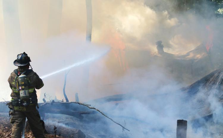 Sunshot by Grayson Williams — Hart County Firefighter Teddy Gibson douses the flames of a fire that burned a vacant mobile home on Whippoorwill Trail on Sept. 25.
