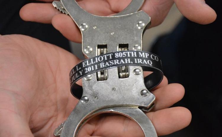 A pair of handcuffs owned by Jonathan Merck that were owned by a friend who was killed in Iraq were used to secure Gabrielle Beutler after she was arrested on charges of making up her veteran status and other charges. Merck wears a bracelet with the name of his friend, SPC Daniel Lucas Elliott. 