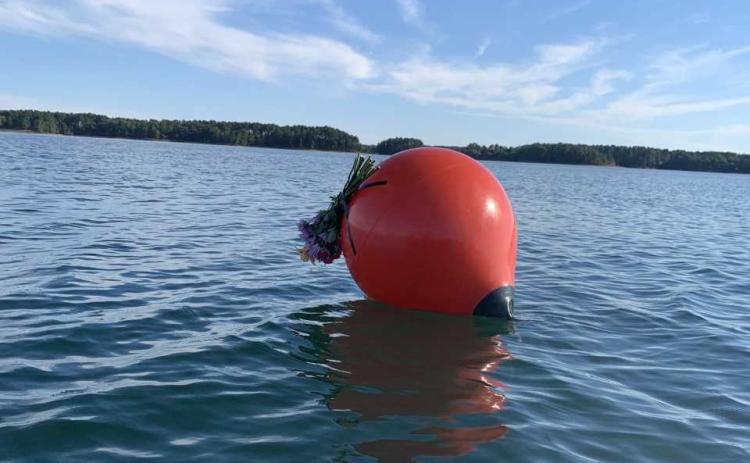 An unknown visitor attached a memorial bouquet Tuesday to the buoy that marks the spot of which a single-engine plane entered Lake Hartwell on Saturday, Sept. 10. The plane was still underwater by press time Wednesday. One passenger, the pilot, was assumed dead upon impact. Excavation crews were scheduled to lift the plane from the lake depths Thursday.