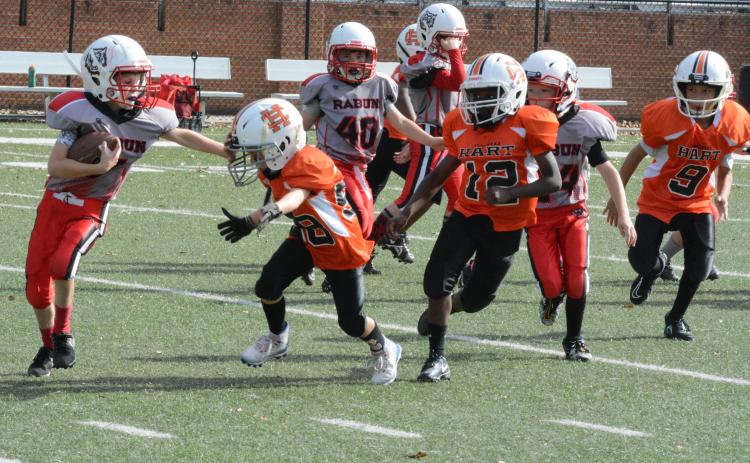 Hart County 7U running back Tristan Gray throws a stiff arm with defender Emmett Wise bearing down. 
