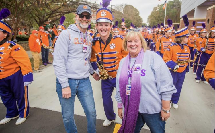 Dawson Baker, center, marches alongside his father Kevin Baker, left, and mother Lisa Baker, right, during Senior Day festivities at Clemson University before kickoff versus the University of Miami.
