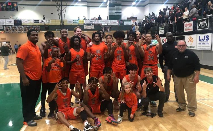 The Hart County boys basketball team holding up eight fingers as they upset Adairsville on the road 68-60 to advance to the elite eight in the Georgia High School boys basketball state tournament.
