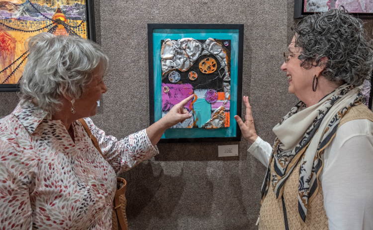Above, (L-R) Lynn Smith and Diana Walter discuss Diana’s art during the Hartwell Art Center’s opening reception for ‘Awakenings’ May 5. Below, art patrons view the artwork in the show. 