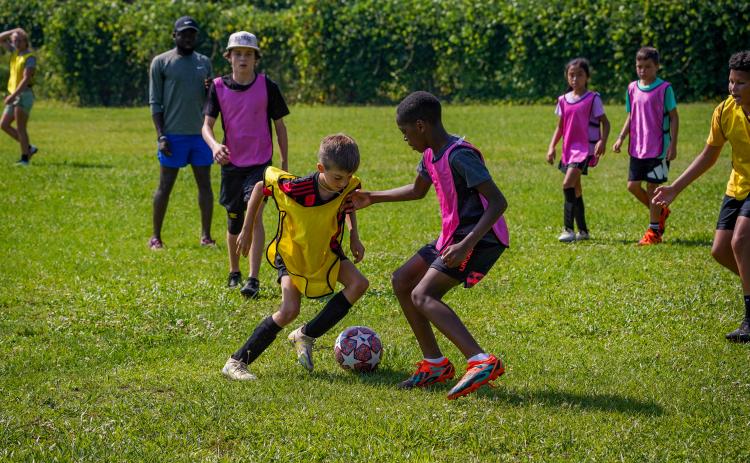 Kingston Durham (left in yellow jersey) tries to dribble around Camber Fenly (right) during the final week of soccer camps at the Bell Family YMCA on June 26-30.