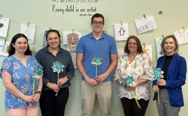 Several members of Harmony House’s team holding blue pinwheels, a reminder of National Child Abuse Prevention Month. Left to right: Kaitlin Andrews, child and family services advocate; Olivia Owensby, director of forensic services; Darrin Haley, clinical director; Wendy Risner, outreach/volunteer coordinator; and Laurie Whitworth, CEO. 